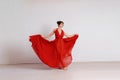 Dancer in a red flying dress. Woman ballerina dancing on a white studio background Royalty Free Stock Photo