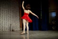 Dancer on stage from the back. Girl in a red dress, white tights and Czechs.