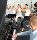 Dancers doing exercises on stretching ballet barre under live music Royalty Free Stock Photo