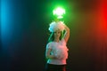 Dancing, cheerleading and people concept - young girl in darkness under colourful light with pompoms on her head