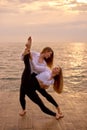 Dancing couple two woman twins training in morning on beach. Two sisters twin girls in identical clothes on ocean background