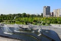 Dancing fountains in the park against the backdrop of tall buildings and skyscrapers. Spring, summer street in city Dnipro,