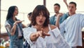 Dancing with friends. Pretty and young woman in white shirt is gesturing and looking at camera while standing on rooftop