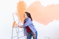 Dancing funny smiling woman painting interior wall of home with paint roller. Redecoration, renovation, apartment repair Royalty Free Stock Photo