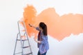 Dancing funny woman painting interior wall of home with paint roller. Redecoration, renovation, apartment repair and Royalty Free Stock Photo