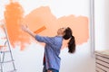 Dancing funny woman painting interior wall of home with paint roller. Redecoration, renovation, apartment repair and Royalty Free Stock Photo