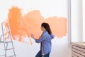 Dancing funny woman painting interior wall of home with paint roller. Redecoration, renovation, apartment repair and Royalty Free Stock Photo