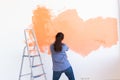 Dancing funny woman painting interior wall of home with paint roller. Redecoration, renovation, apartment repair and Royalty Free Stock Photo