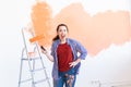 Dancing funny young woman painting wall in her new apartment. Renovation, redecoration and repair concept. Royalty Free Stock Photo