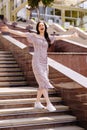 Dancing girl feeling happy in city.Young woman dancing and listening music in headphones, standing on the stairs in park