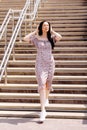 Dancing girl feeling happy in city.Young woman dancing and listening music in headphones, standing on the stairs in park