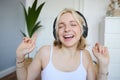 Dancing girl listens to music, woman wears wireless headphones and enjoys sound quality, sings Royalty Free Stock Photo