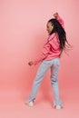 Studio shot of young excited girl with afro hairdo in casual style outfit having fun isolated on pink background Royalty Free Stock Photo