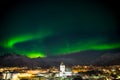 Dancing green polar lights over the town Svolvaer on the Lofoten islands in Norway at night in winter with snow