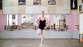 In dancing hall, Young ballerina in black leotard performs grand jete pat de chate , She moving through the ballet class