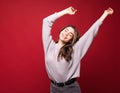 Dancing happy cheerful woman in red in joyful dance. Energetic portrait of joyous beautiful young woman on red background