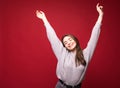 Dancing happy cheerful woman in red in joyful dance. Energetic portrait of joyous beautiful young woman on red background