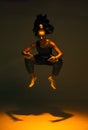 Dancing mixed race girl jumping and levitating in spotlight in studio. Female dancer show expressive hip hop dance Royalty Free Stock Photo
