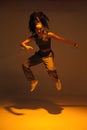 Dancing mixed race girl jumping and levitating in warm studio light. Female dancer performer jump in hip hop dance Royalty Free Stock Photo
