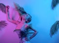 Dancing in neon. A girl with long blonde hair is dancing at a beach party. Summer dance to the music on the background of tropical Royalty Free Stock Photo