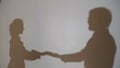 Two silhouettes of young belovers. Reflection of their shadows on the wall. Dancing shadows on the wall of a guy and a Royalty Free Stock Photo
