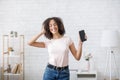 Dancing with smartphone when home alone. Happy african american woman with closed eyes with headphones sing song with Royalty Free Stock Photo