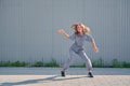 Dancing teen girl happy rhythmically moving against textured street fence. Energetic cool teen female dancer having fun