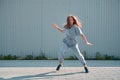 Dancing teen girl showing hip hop dance on urban background. Energetic young dancer cool moving on street