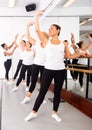 Dancing women perform the battement tendu movement near a barre, where the choreographer helps to perform the exercise Royalty Free Stock Photo