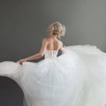 Dancing young bride in luxurious wedding dress. Pretty girl in white. Back, gray background Royalty Free Stock Photo