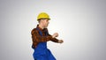 Dancing young engineer with helmet after work on gradient background.