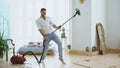 Young man having fun cleaning house with vacuum cleaner dancing like guitarist Royalty Free Stock Photo