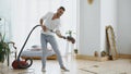 Young man having fun cleaning house with vacuum cleaner dancing Royalty Free Stock Photo