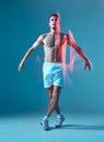 Dancing young muscular shirtless male performing modern zumba dance in studio. Motion blur, long exposure