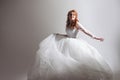 Dancing young woman in wedding dress. Charming bride on Light background with a shadow Royalty Free Stock Photo