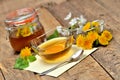 Dandelion honey, herbal tea, full jar of honey, spring flower, fresh mint leaves, spoon and dandelion head around - Royalty Free Stock Photo