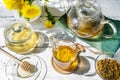 Dandelion tea and honey on the white wooden table with tea pot, dandelion flowers, dry mix for tea Royalty Free Stock Photo