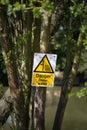 Danger Deep Water warning sign on a tree. Lake in the background Royalty Free Stock Photo