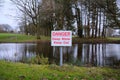 danger deep water warning sign by a water filled pond risk to the public Royalty Free Stock Photo