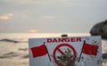 Danger do not swim sign with two red flags, blurred sea in background