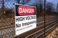 Danger, high voltage, no trespassing sign on a fence in front of a rail road Royalty Free Stock Photo