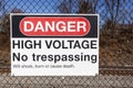 Danger, high voltage, no trespassing sign on a fence in front of a rail road Royalty Free Stock Photo