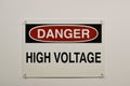 Danger High Voltage plastic warning sign isolated and attached to a white wall with push pins. Royalty Free Stock Photo