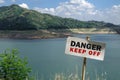 Danger Keep Off Sign With Dam Lake