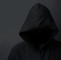 Danger lurking in the dark. an unidentifiable hooded man posing against a dark background. Royalty Free Stock Photo