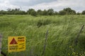 `Danger Mines` yellow warning sign, in Hebrew, Arabic and English, next to a mine field Royalty Free Stock Photo