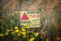 Danger mines - yellow warning sign next to a mine field, close to the border with Syria, in the Golan Heights, Israel