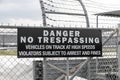DANGER NO TRESPASSING - VEHICLES ON TRACK AT HIGH SPEEDS VIOLATORS SUBJECT TO ARREST AND FINES sign at a race track