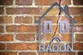 The danger of radon gas in our homes - concept image with an outline of a small house with radon text against a cracked brick wall