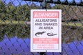 Danger sign Alligators and Snakes posted by a lake at a park in Florida